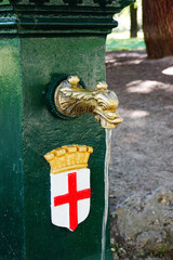 Drinking water fountain with golden details and the flag of the city in a park of Milano, Italy
