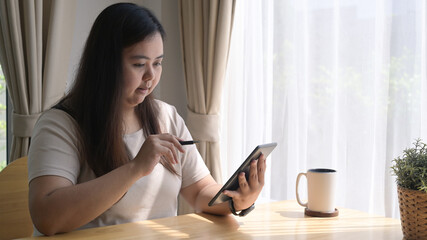 Pretty using woman working online, surfing internet on digital tablet at home.