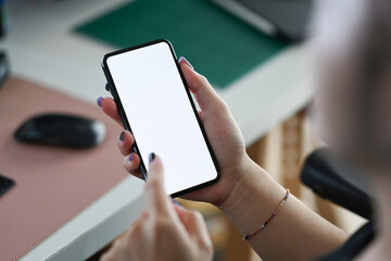 Over shoulder view stylish male using mobile phone while working at home office.