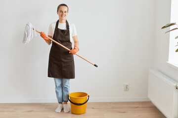 Full length photo of Caucasian housewife general cleaning disinfecting all surfaces, holding mop,...