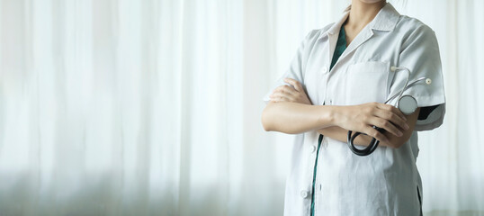 Female doctor holding stethoscope standing on light background. Healthcare, medicine, health insurance concept.