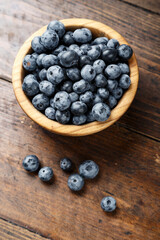 Freshly picked blueberries in wooden bowl on wooden background.  Concept of healthy and dieting eating.