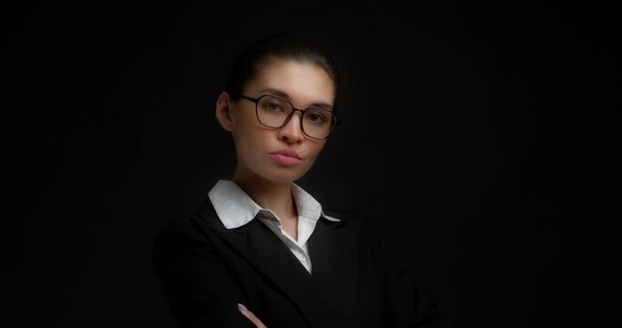 Beautiful confident businesswoman adjusts the lapel on her jacket. A female boss with glasses adjusts the collar of a white shirt and being ready for new business day on an isolated black background