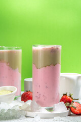 Natural healthy summer drink. Diet organic strawberry and matcha latte cocktail, with fresh strawberry and ice, on a white light green background