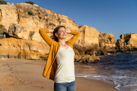 Smiling woman with eyes closed standing at beach