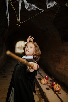 Girl wearing witch costume having fun in spooky tunnel at Halloween
