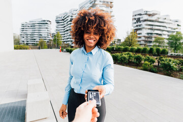 Smiling businesswoman receiving contactless payment from man holding credit card