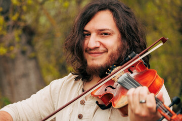 Smiling man with long hair playing violin