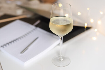 A glass of white wine on the desk.