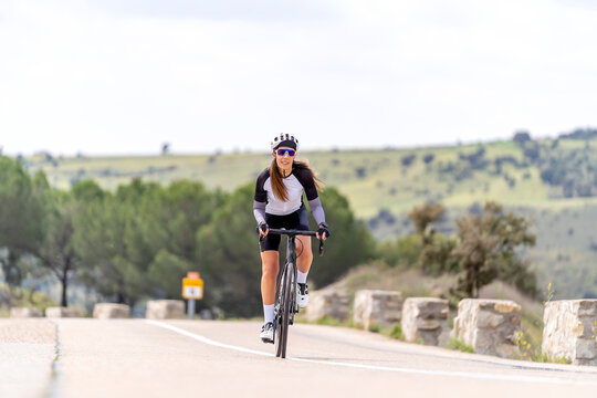 Sportswoman wearing sports helmet riding bicycle on road