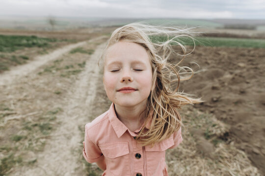 Blond girl with eyes closed standing in agricultural field