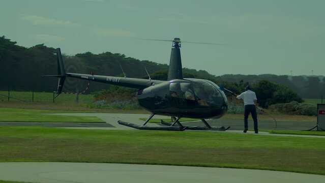 Ground crew wash the windscreen of a Robinson R44 helicopter before ity takes off on another scenic tour over the 12 Apostles,