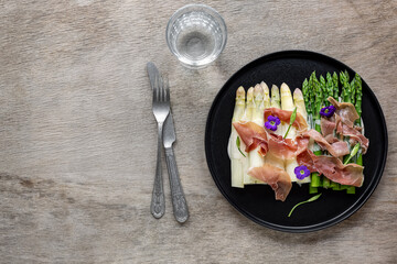 White and green asparagus with prosciutto ham and sauce. Great seasonal food, easy cooking meal for keto diet dinner or lunch.