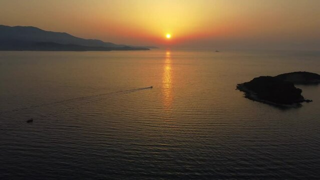 Drone shot of a sunset at Albanian coast, Mediterranean sea - drone is ascending while the sunset is getting revealed. Snippet could ideally be used for travel related videos or movies.