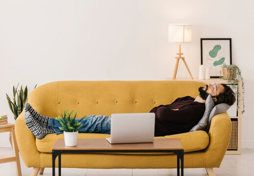 Man with eyes closed relaxing on sofa in living room at home