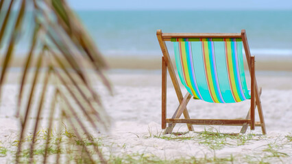 Colorful beach chair on the beach and sea waves and blue sky in the background.