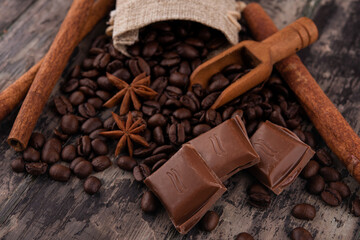 chocolate, cinnamon sticks  and coffee beans on wooden background
