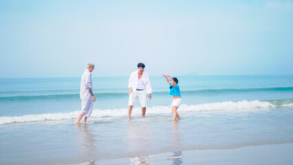 Grandfather and grandmother are playing with their little granddaughter on the beach.