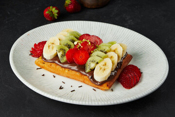 Belgium waffle with fruits and chocolate paste on plate