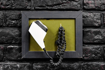 Old electric razor with curved cable in frame hangs on wall