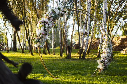 Wedding arch with fresh flower garlands on lawn in park