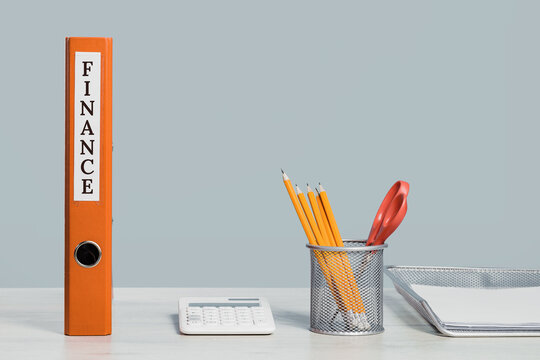 Finance orange document binders or lever arch file with paperwork on an office shelf or desk. Calculator and pencils. Business concept banner. Copy space