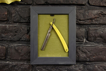 Straight razor in frame on grunge brick wall in barbershop