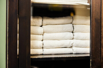 Stacks of clean tidy towels on cabinet shelf with glass door