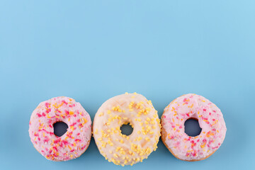 pink and yellow sprinkled  donuts on a blue background Space for text