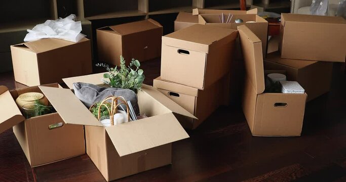 Living room with heap of packed cardboard boxes with personal belongings and interior design items at relocation or move-out day, no people. Tenancy, affordable dwelling, bank loan, new life concept