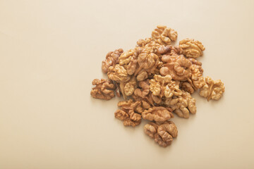 Peeled halves of walnuts top view on beige background