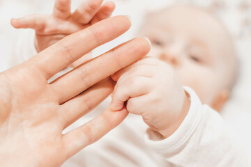 The baby holds with both hands the mothers hand touches and examines her. The emotional bond...