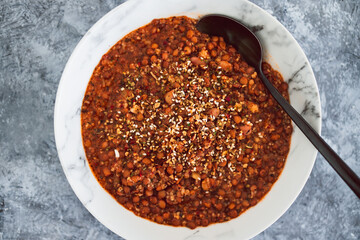vegan lentil and couscous ragu with herbs and dukkah as topping, healthy plant-based food
