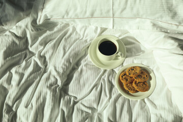 Cup of coffee and cookies on the bed