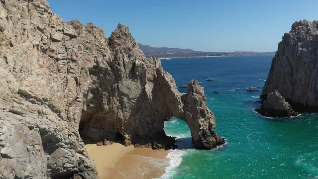 Aerial shot of El Arco and Playa del Amor slowly revealing boats in the ocean in Cabo San Lucas Mexico
