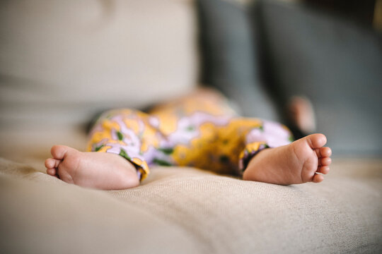 Bare feet of newborn baby sleeping on sofa