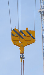 Crane hook hanging on steel ropes on background sky