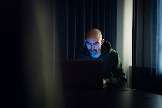 Man working on laptop in dark office