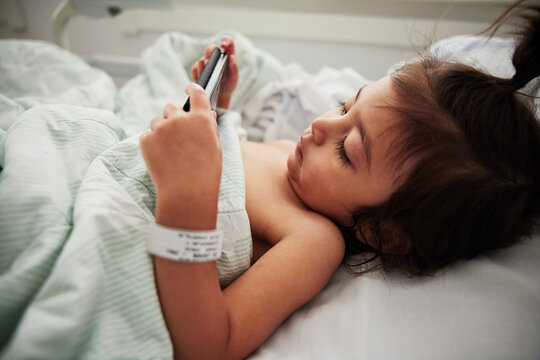 Girl using phone in hospital bed