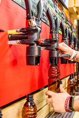 bartender hand at beer tap pouring a draught beer in bottle in tap room