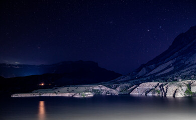 night landscape on the lake with mountains against the background of the starry sky