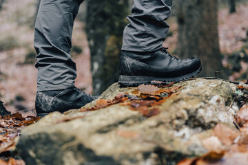 Close up detail photo of hiking or trekking boots in muddy autumn trail. Mountain leather shoes on...