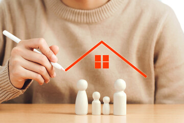 Family life and property insurance concept. women hand drawing houses on Wooden figurines represent...
