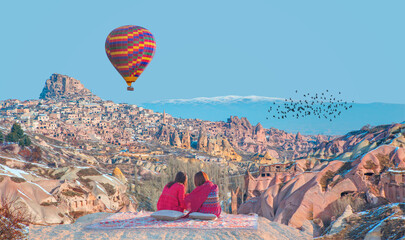 Hot air balloon flying over spectacular Cappadocia - Japanese girls watching hot air balloon at the...