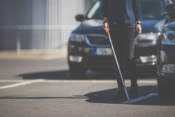 Blind woman walking on city streets, using her white cane to navigate the urban space better and to...