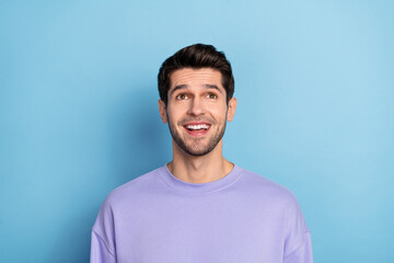 Fototapeta premium Photo of impressed millennial brunet guy look up wear sweatshirt isolated on blue color background