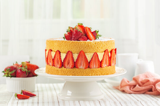 Festive French Fraisier Cake made with two layer of Genoise Sponge, Diplomat Cream and Fresh Strawberries. Delicious Summer Fruit Cake with fresh berries on a holiday table.