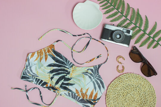 Beach concept with camera, sun glasses and bikini bra over the pink background. 