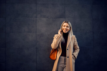 A smiling woman having phone conversation outside.