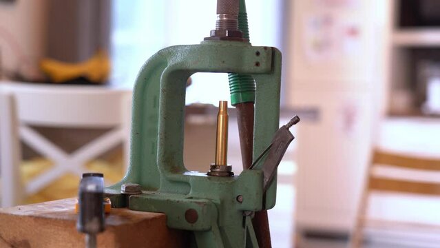 Person using single stage reloading press to insert bullet to cal 3006 rifle brass casing - Reloading of ammunition process at home